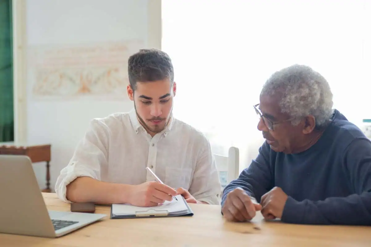 Caregiver helping a senior man prepare for an ACAT assessment in WA by writing down his daily support needs