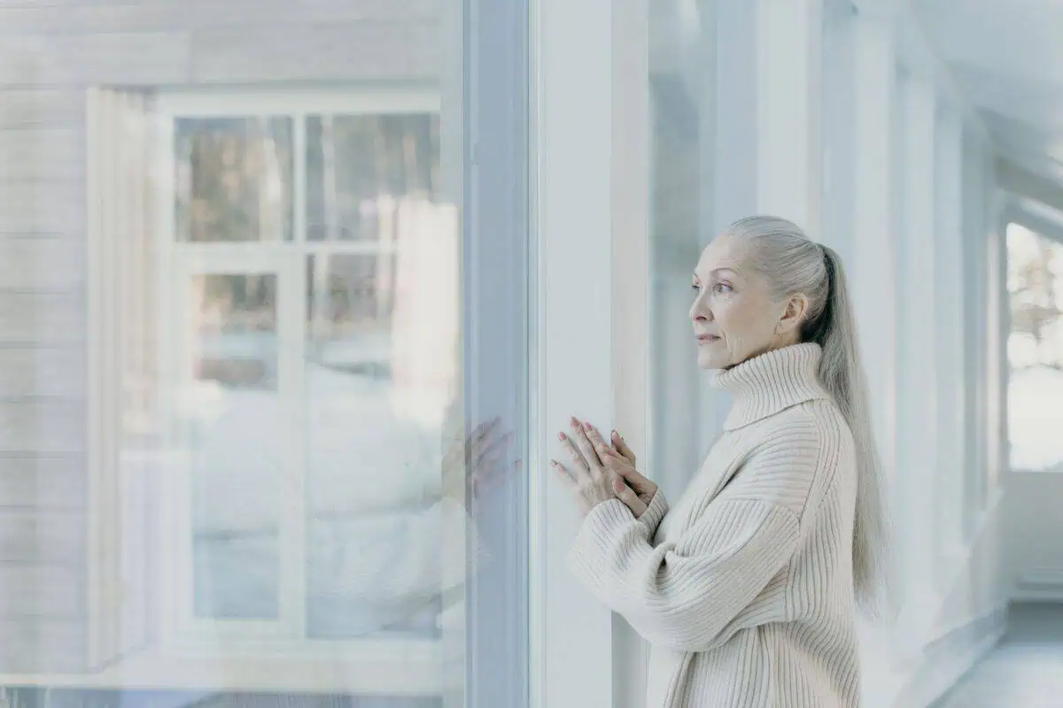 Older woman looking out of a window and wondering whether it is a new dawn or another doorstop for aged care
